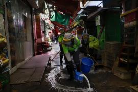 Fotografie dintr-o piață din China. Muncitorii dezinfectează zona