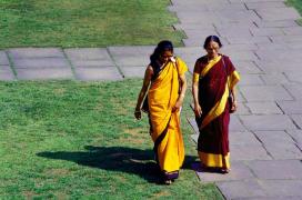 Două femei în sari merg alături pe o străduță dintr-un oraș indian. Imagine ilustrativă