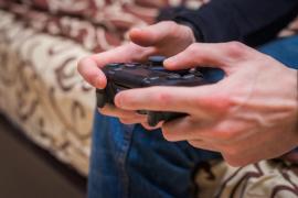 Vedere din spate a jucătorului cu controlerul gamepad al consolei video în mână