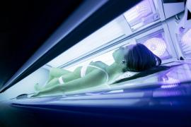 Femeie în cabina cu ultraviolete a unui salon de bronzat