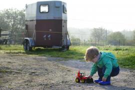 În imagine: Un copil se joacă cu o maşină de jucărie
