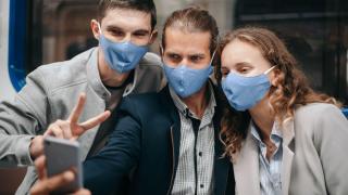 Trei prieteni își fac un selfie în oraș în timp ce poartă măști de protecție