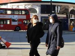 Tinere cu mască de protecție pe față se plimbă prin Londra