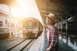 În imagine: O femeie cu pălărie, pe un epron, în gară