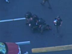 Momentul în care suspectul este imobilizat de polițiști, un agent ține un bebelus in brațe