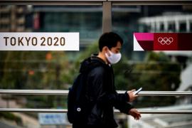 Un om trece pe lângă logo-urile bannerelor Jocurilor Olimpice de la Tokyo 2020 din Tokyo