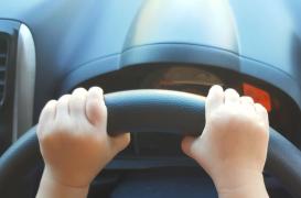 Mainile unui copil pe volanul unei masini reale