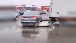 Jaguar parcat pe rampa unei autoutilitare, în parcarea aproape goală unui hypermarket din București