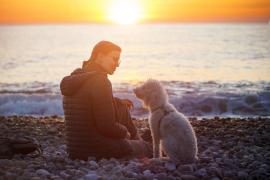 femeie cu un cățel pe malul mării