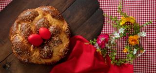 Ouă roşii de Paşte şi cozonac aşezate pe masă, alături de flori