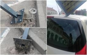 O maşină parcată, avariată de un indicator electronic montat recent. Piciorul de metal, prins în asfalt cu dibluri de tablouri