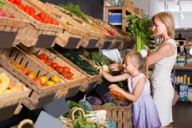 O mamă şi fiica ei fac cumpărături la raionul de fructe şi legume