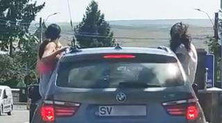 Tinere ieșite pe geamurile unui BMW în mers, cocoțate pe portiere. Fetele puse pe distracție, filmate pe un drum din Suceava
