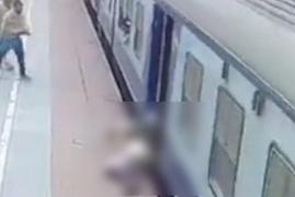 Momentul dramatic când un bărbat este prins sub trenul pus în mișcare. Este salvat în ultimul moment de călătorii aflați pe peron, în India