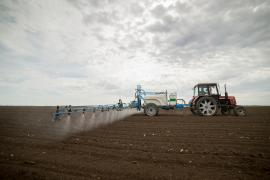 Tractor care împrăștie pesticide pe un câmp