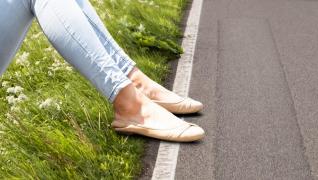 Femeie stând pe asfalt, purtând balerini