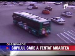 Un baietel de trei ani cu scuterul pentru copii in mijlocul unei intersectii aglomerate