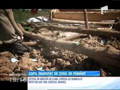 Copil îngropat de un perete de pământ