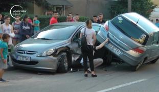 Scenă ca-n filme pe o stradă din Reşiţa. O maşină s-a urcat cu două din roţi pe un autoturism parcat