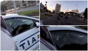 Un poliţist stă pe telefon la volan, într-o intersecţie în care maşinile trec pe roşu pe lângă el (video)