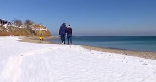 Soare şi ger la malul mării. Mulți turiști au înfruntat frigul de dragul unei plimbări pe nisipul acoperit de zăpadă