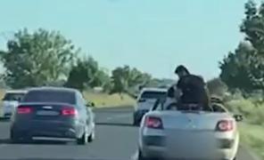 Un bărbat a fost filmat în timp ce se ridică în picioare pe bancheta unei decapotabile, pe E85. O fetiţă îi imită gestul