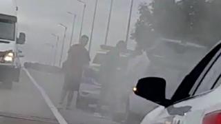 Un poliţist din Suceava se dă jos din autospecială și stinge o mașină cuprinsă de flăcări care se afla în coloană, pe un pod, în fața lui