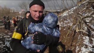 Un soldat ucrainean fuge cu un bebeluș ce-i plânge în brațe, ca să-l scape din bombardamentele de la Irpin