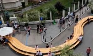 O masă uriaşă, şerpuitoare, tronează într-o piaţetă din centrul Capitalei. Oamenii şi-au dat întâlnire şi stau la taifas, în intersecţie