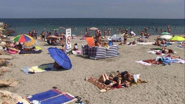 Turişti pe plajă pe o vreme frumoasă