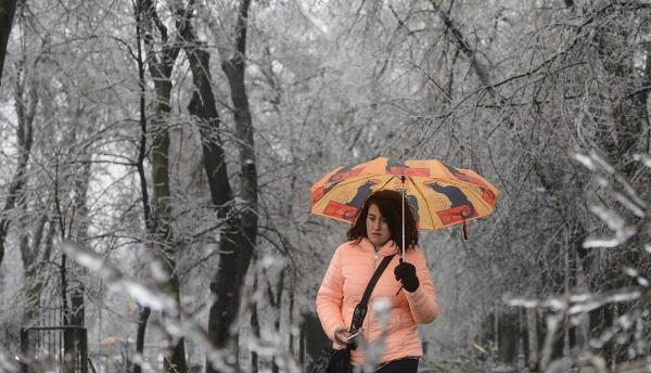 O femeie merge pe o alee într-un parc din Bucureşti, afectat de ploaia îngheţată
