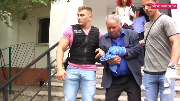 Vasile Tofan încadrat de polițiști după reconstituirea crimei