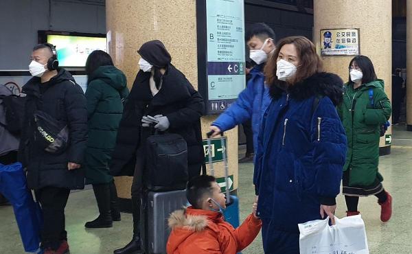 Oamenii care poartă măști de protecţie de față se plimbă pe o stradă, în Beijing, China.