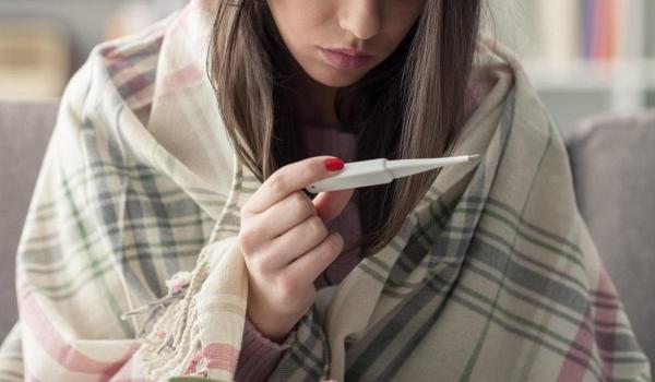 O tânără îşi ia temperatura cu termometrul