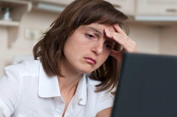 O femeie prezintă stări de oboseală în timp ce lucrează la laptop.