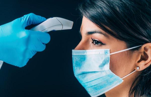 Femeie cu mască de protecţie testată pentru temperatură