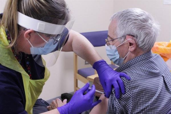 Un bătrân din Marea Britanie este vaccinat de o asistentă împotriva coronavirusului.