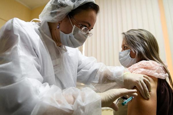 Doctor și pacient cu măști de protecție, în timpul administrării unui vaccin