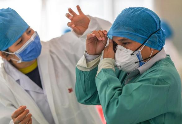 Doi medici se îmbracă cu costume de protecţie