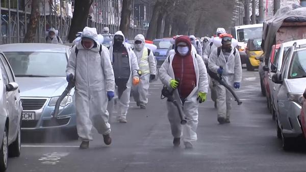 Muncitorii împrăștie dezinfectant pe o stradă aglomerată din București