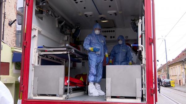 Paramedici în combinezoane în ambulanţa de transport pacienţi de coronavirus