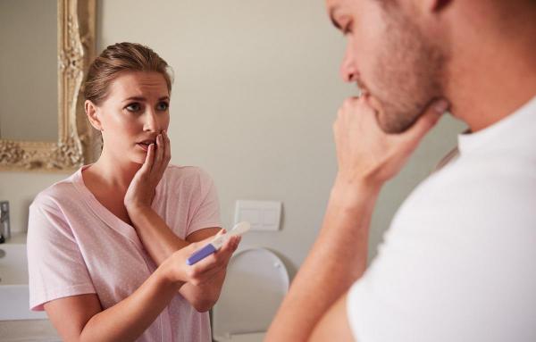 O femeie arată unui bărbat un test de sarcină