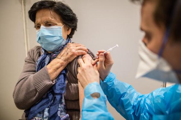 O pacientă care poartă mască primește o doză de vaccin Pfizer BioNTech