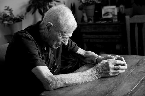 Bătrân singur cu capul în jos şi mâinile împreunate