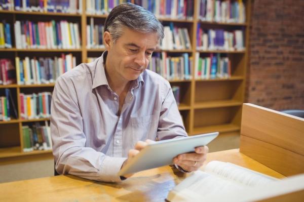 Profesor folosind o tabletă, într-o bibliotecă