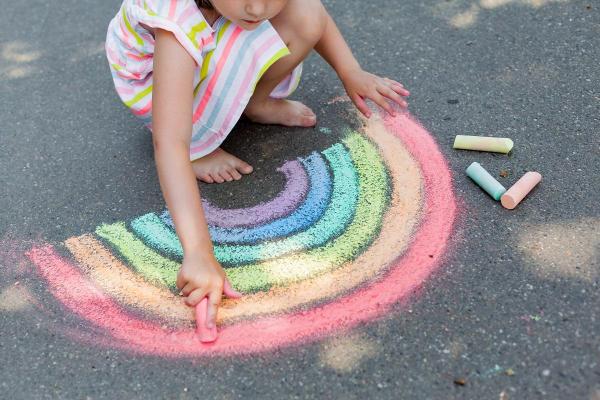 Fetiţă care desenează cu creta pe trotuar