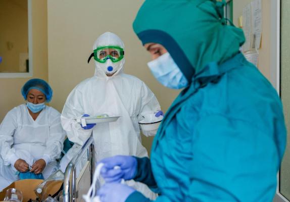 Un medic îmbrăcat în costum de protecţie face teste covid