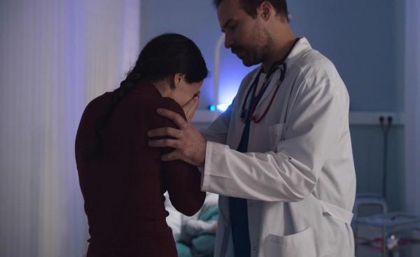 În imagine: O femeie plânge lângă un medic, în spital