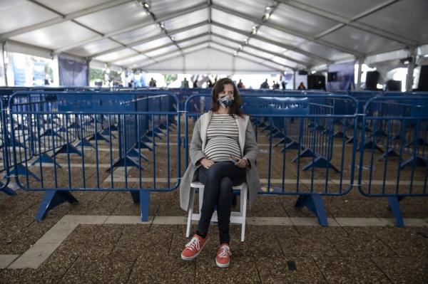 Shira Weinberg ,36, eight months pregnant, rests after receiving the Pfizer-BioNTech coronavirus vaccine at a COVID-19