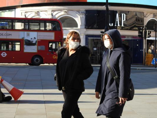 Tinere cu mască de protecție pe față se plimbă prin Londra